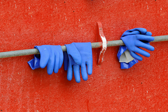 Blue gloves against red wall